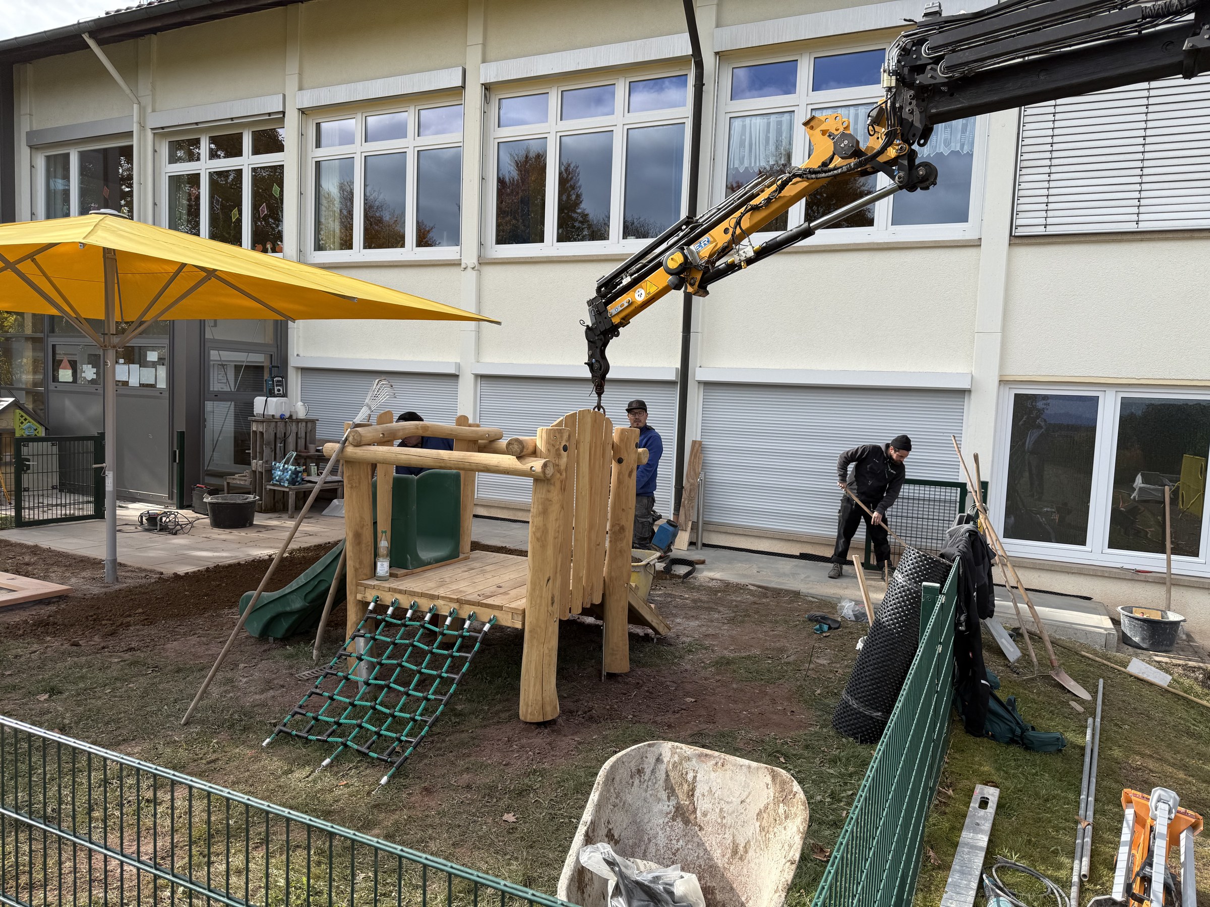 Bagger und neues Spielhaus auf der Baustelle im Kita-Garten